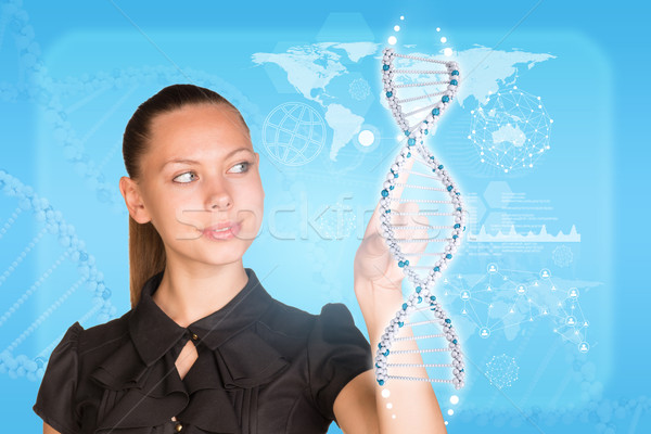 Beautiful businesswoman in dress smiling and presses finger on model of DNA Stock photo © cherezoff