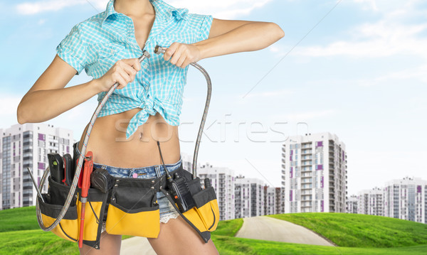 Woman holding two flexible hose. Cropped image. Green hills with road and buildings on background Stock photo © cherezoff