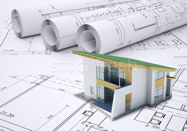 Stock photo: Small model house with green roof near scrolls of architectural drawings