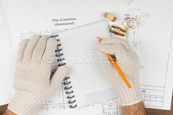 Man writing in pad with pipe fittings Stock photo © cherezoff