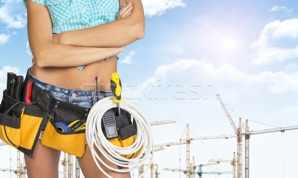 Woman in tool belt stands his arms crossed. Cropped image. Tower cranes as backdrop Stock photo © cherezoff