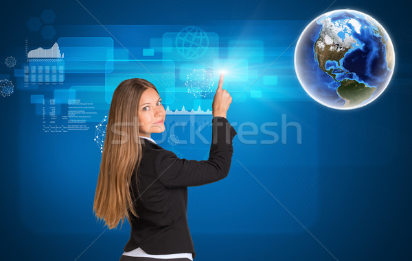 Businesswoman standing back and looking at camera pressing on holographic screen Stock photo © cherezoff