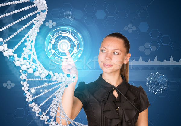 Beautiful businesswoman in dress smiling and presses finger on model of DNA Stock photo © cherezoff