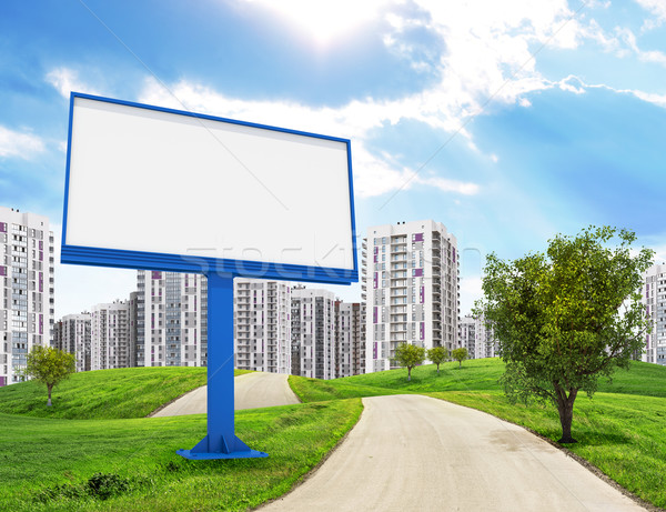 Blank billboard and tree by road running through green hills leading toward city, I Stock photo © cherezoff