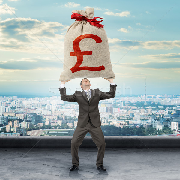 Businessman holding big moneybag with pound sign Stock photo © cherezoff
