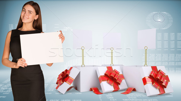 Stock photo: Businesswoman holding empty paper. Open gift boxes with blank labels