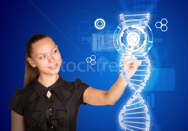 Beautiful businesswoman in dress smiling and presses finger on model of DNA Stock photo © cherezoff
