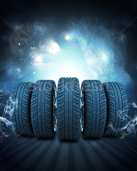 Wedge of new car wheels. Background is night sky and stripes at bottom Stock photo © cherezoff