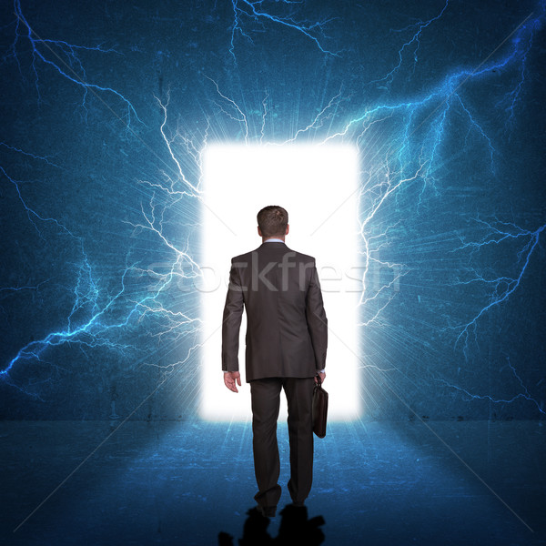 Businessman in suit with briefcase stepping through door Stock photo © cherezoff