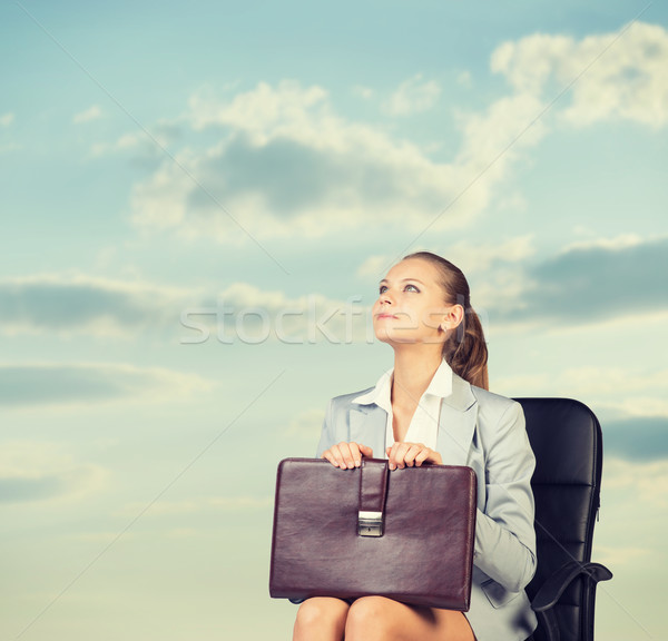 Business woman in skirt, blouse and jacket, sitting on chair. Against background of sky, clouds Stock photo © cherezoff