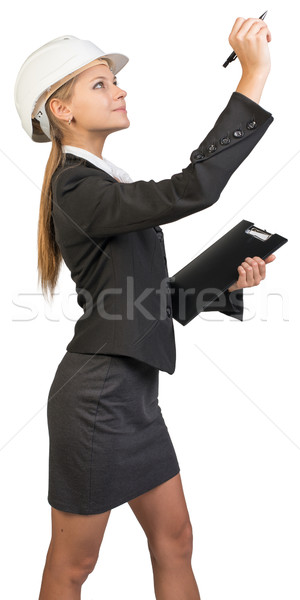 Businesswoman wearing hard hat, holding clipboard, drawing or writing something up in the air Stock photo © cherezoff