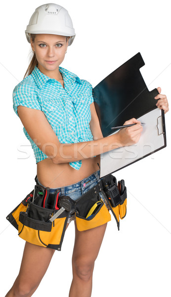 Woman in hard hat and tool belt writing on blank clipboard Stock photo © cherezoff