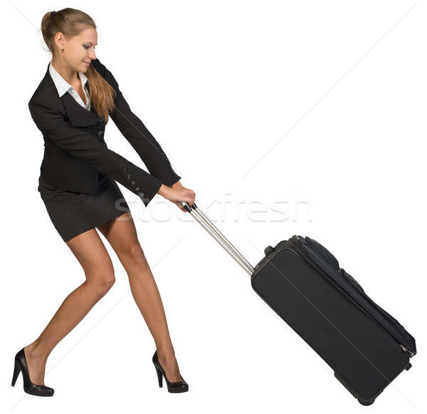 Businesswoman dragging heavy wheeled suitcase with both hands Stock photo © cherezoff