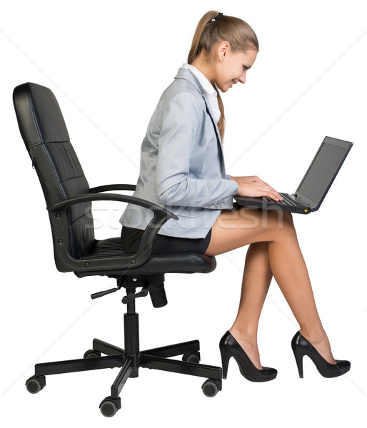 Businesswoman on office chair operating laptop  Stock photo © cherezoff