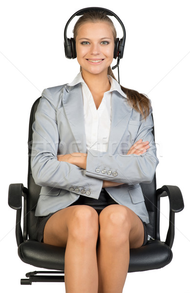 Femeie de afaceri setul cu cască şedinţei scaun de birou zâmbitor cu bratele incrucisate Imagine de stoc © cherezoff