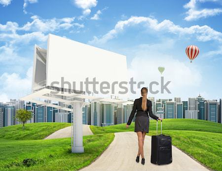 Businessman walks on road. Rear view. City skyline, grass field, wooden signboard and sky in backgro Stock photo © cherezoff