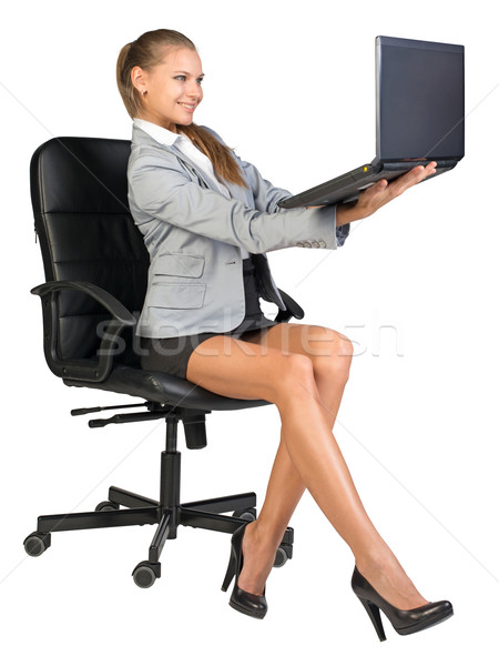 Businesswoman on office chair, holding laptop in her arms at eye level Stock photo © cherezoff