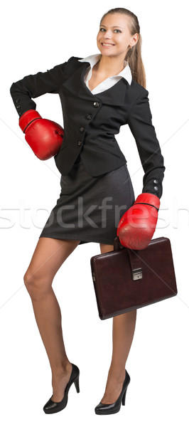 Businesswoman wearing boxing gloves standing akimbo Stock photo © cherezoff