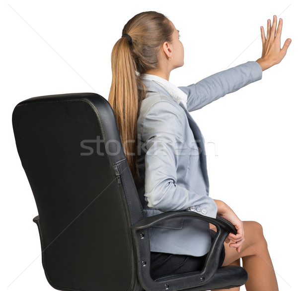 Businesswoman on office chair, with her hand reached upwards and ahead, palm outward Stock photo © cherezoff