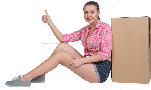 Woman sitting next to cardboard box, giving thumb up Stock photo © cherezoff