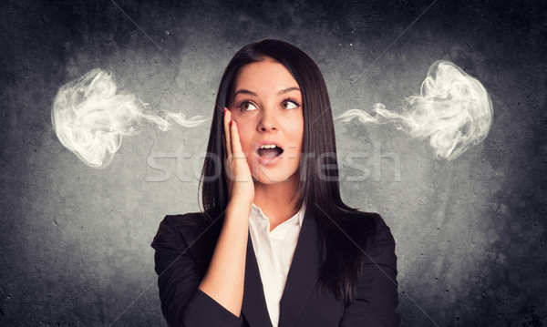 Surprised woman with steam from ears. Concrete gray as backdrop Stock photo © cherezoff