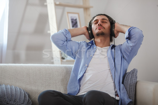 Handsome guy sitting on sofa with headphones Stock photo © chesterf