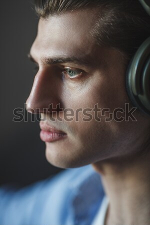 Stock photo: Music in his mind. Portrait of young man wearing headphones and looking away