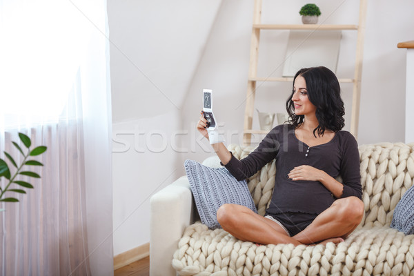 happy beautiful pregnant woman relaxing on sofa with echo in hands Stock photo © chesterf