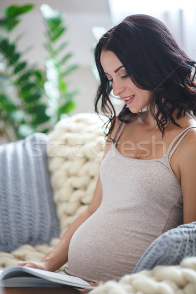 Zâmbitor femeie gravida şedinţei canapea lectură revistă Imagine de stoc © chesterf