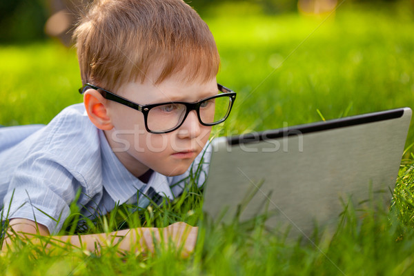 Stock photo: boy laying on grass in the park with laptop