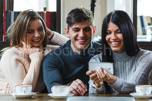 Group of friends with coffee and looking at smartphone Stock photo © chesterf