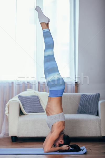 Beautiful young woman dressed in sportswear doing yoga indoors. Stock photo © chesterf