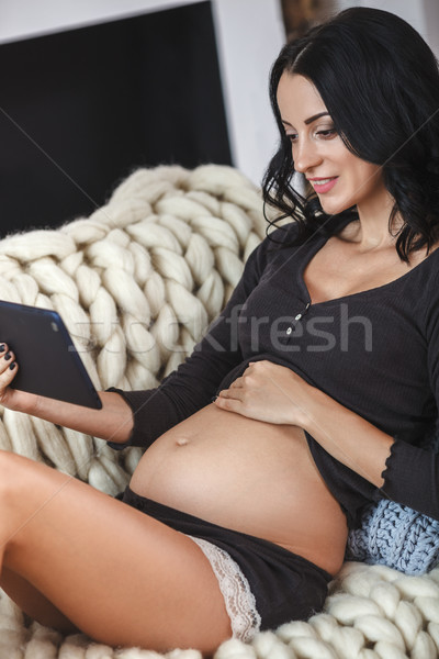 Happy pregnant woman on couch at home, using a digital tablet Stock photo © chesterf