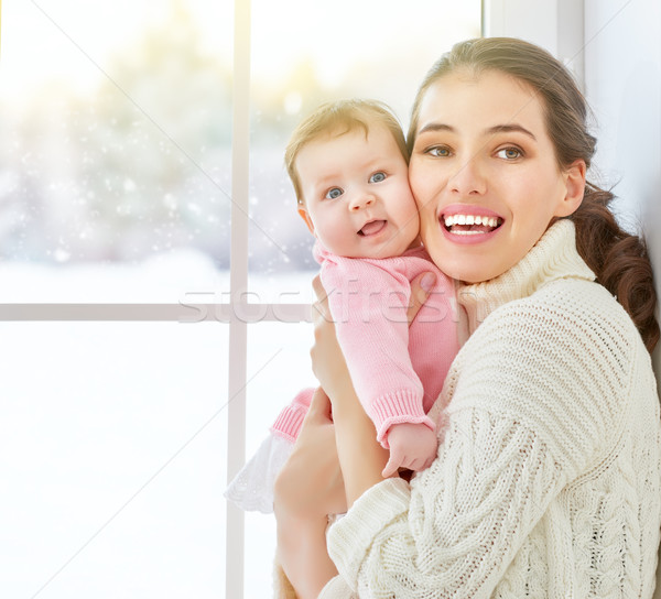 Mother and baby hugging near window. Stock photo © choreograph