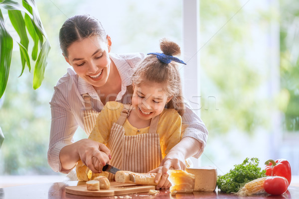Stock photo: Mother and daughter cut bread and cheese