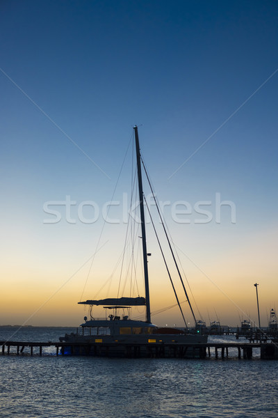 Sunset at marina with docked yacht and calm sea Stock photo © cienpies