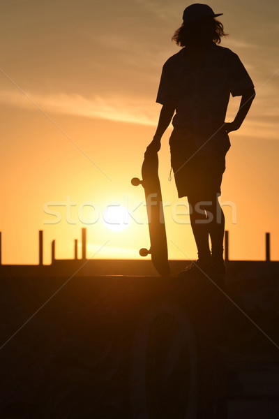 Teenager boy silhouette with skate board at sunset Stock photo © cienpies