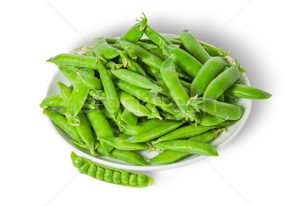 Opening and closing pea pods on white plate top view Stock photo © Cipariss