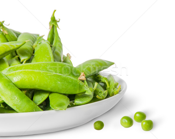Closeup pile of green peas in pods in white plate Stock photo © Cipariss