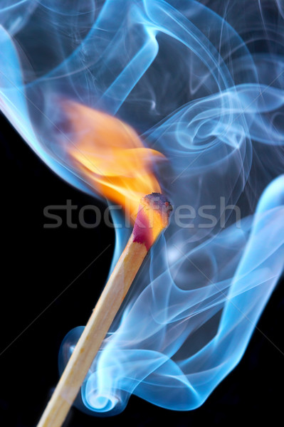 Stock photo: Photo of a burning match in a smoke on a black background