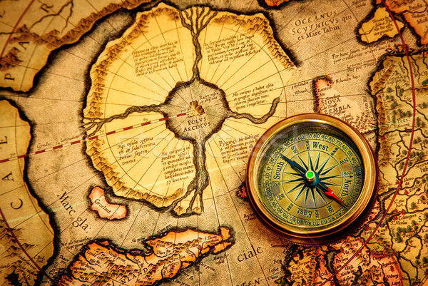 Vintage compass lies on an ancient map of the North Pole. Stock photo © cookelma