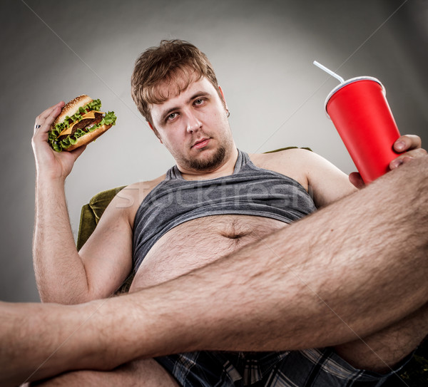 Gros homme manger hamburger assis fauteuil style [[stock_photo]] © cookelma