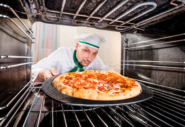 Chef cooking pizza in the oven. Stock photo © cookelma