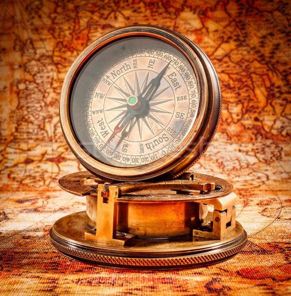 Vintage compass lies on an ancient world map. Stock photo © cookelma