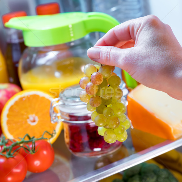 Woman takes the bunch of grapes from the open refrigerator Stock photo © cookelma