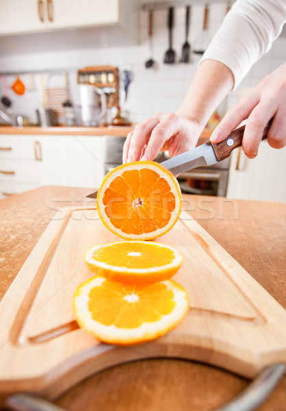 Stock photo: Woman's hands cutting orange