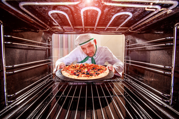 Chef cooking pizza in the oven. Stock photo © cookelma