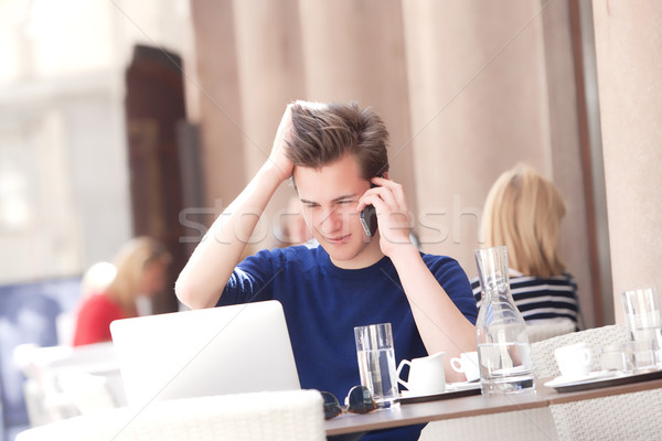 Young Man Sitting in Outside Coffeehouse Talking on Phone Stock photo © courtyardpix
