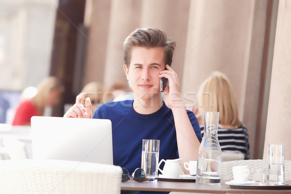 Young Man Sitting in Outside Coffeehouse Talking on Phone Stock photo © courtyardpix