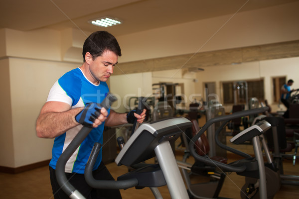 Man exercising on elliptical machine in gym Stock photo © d13
